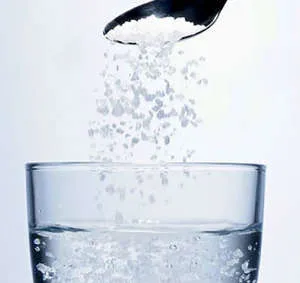 Насыпание соли в стакан с водой