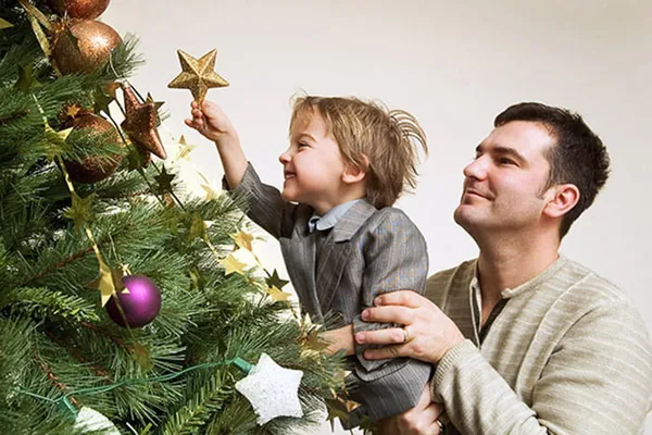 Ребенок с отцом украшает елку